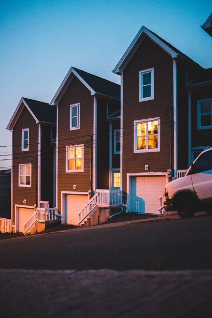 A serene view of modern houses on a sloped street under a twilight sky, exuding warmth and coziness.